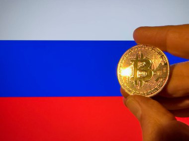 Rus bayrağı üzerinde fiziksel olarak altın bir Bitcoin taşıyor. Rusya kripto para birimi ve engelleme teknolojisi yatırımcısı. Fotokopi alanı ile finansal geçmiş. Merkezi olmayan sanal para kavramı.