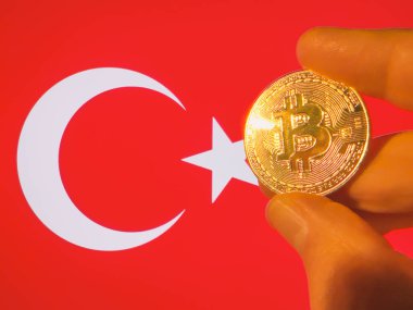 Türk bayrağı üzerinde fiziksel olarak altın bir Bitcoin taşıyor. Türkiye kripto para birimi ve engelleme teknolojisi yatırımcısı. Fotokopi alanı ile finansal geçmiş. Merkezi olmayan sanal para kavramı.