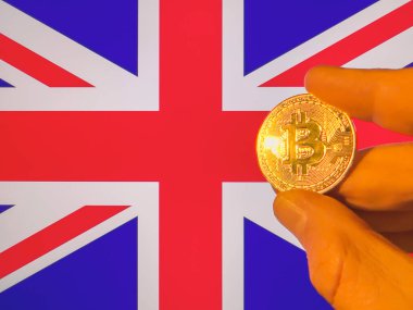 İngiliz bayrağı üzerinde fiziksel olarak altın bir Bitcoin taşıyor. İngiltere kripto para birimi ve engelleme teknolojisi yatırımcısı. Fotokopi alanı ile finansal geçmiş. Merkezi olmayan sanal para kavramı.