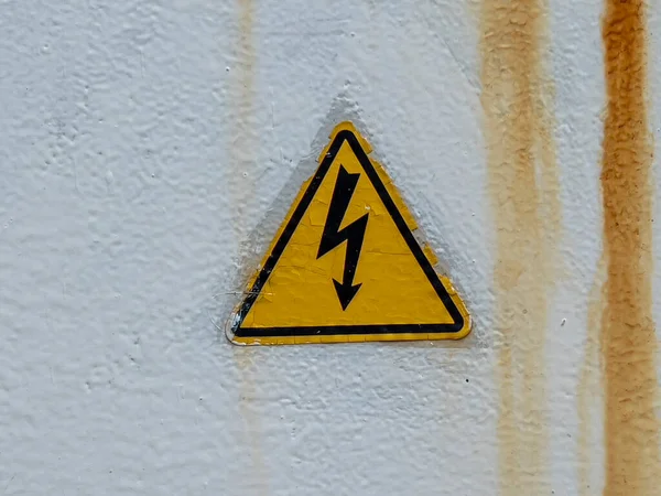 Yüksek voltaj işareti. Kopya uzayı ile yıpranmış arka planda elektrik şoku üçgeni sembolü riski. Tehlike sembolü. Sarı üçgene izole edilmiş siyah ok. Uyarı simgesi.