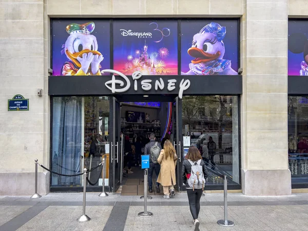 Paris, Fransa. 06.17.2022. Ünlü Champs Elysees Bulvarı 'ndaki Disney mağazasının giriş tabelası. İnsanlar dikiz aynasından kapıda sıraya giriyor. Alışveriş merkezinin vitrininde 30 'uncu yıl dönümü posteri.