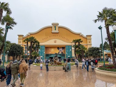 Paris, Fransa - 04 / 05 / 2022: Su kulesi ve Disneyland Paris 'teki Walt Disney Stüdyoları' nın giriş kemeri. Hava bulutlu. Kapıya doğru yürüyen insanlar.