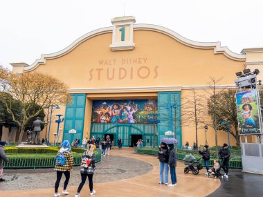 Paris, Fransa - 04 / 05 / 2022: Disneyland Paris 'teki Walt Disney Stüdyoları bulutlu ve yağmurlu havalarda. İnsanlar etrafta dolanıp kapıdan içeri giriyor..
