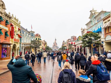 Paris, Fransa - 04 / 05 / 2022: Bulutlu havada Uyuyan Güzel Kalesi. İnsanlar Disneyland Parkları 'nın ünlü ve simgesel binasına yürüyorlar..