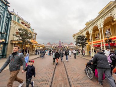 Paris, Fransa - 04 / 05 / 2022: Disneyland 'deki ana alışveriş yolu. İnsanlar Disneyland Parkları 'nın ünlü ve simgesel binasına yürüyorlar. Komik dükkanlar