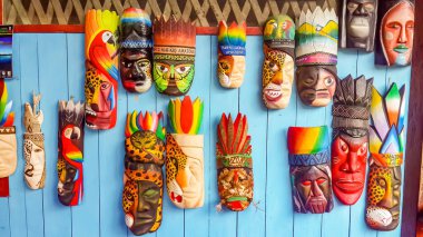 Puerto Narino, Kolombiya - 15 Şubat 2017: Leticia 'daki yerel köy pazarında satılık Maya ahşap maskeleri. Amazonların Nehri 'nde renkli el yapımı sanat eserleri. İnka tanrıları dekorasyon için maskeyle yüzleşir.