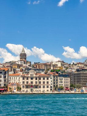 Galata Tower and new cruise customs port building, view from sea on a sunny day. Beautiful ancient city of Istanbul at daylight. Vertical blue sea and sky background. Travel destination. 