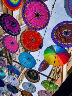 Colorful hanging umbrellas in various designs and shapes hanging between residential apartments in a district in Istanbul, Turkey, directly above. Creative background for rain and sunlight protection