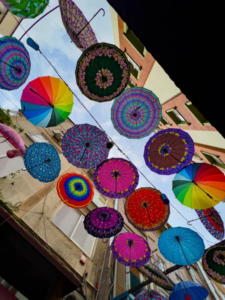 Colorful hanging umbrellas in various designs and shapes hanging between residential apartments in a district in Istanbul, Turkey, directly above. Creative background for rain and sunlight protection