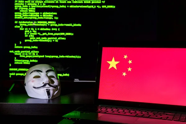 带着仇杀面具的中国匿名黑客背景中的中国国旗和程序代码 — 图库照片