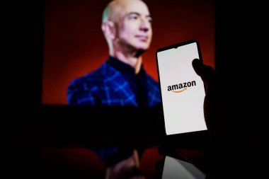 Amazon logosu ekranda ve Jeff Bezos arka planda Amazon 'un yönetici başkanı.