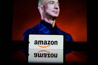 Amazon logosu ekranda ve Jeff Bezos arka planda Amazon 'un yönetici başkanı.