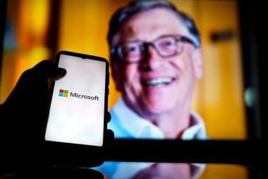 Ekranda Microsoft logosu ve arka planda Bill Gates. Microsoft 'un kurucularındandır.