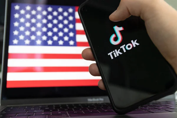 Kaunas, Lithuania - 2022 June 28: TikTok app on smartphone and United states of America flag in background.