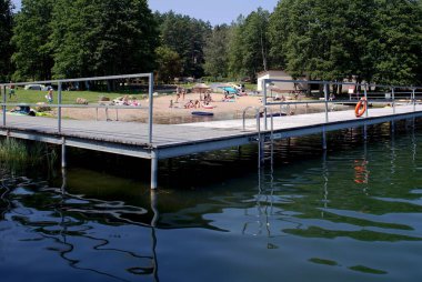 Swieszyno, Poland - 07-20-2022: Beach and a wooden bridge by the lake