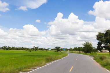 Asfalt yol ve bulutların üstünde mavi gökyüzü.