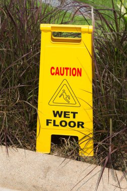 Yerler ıslak diye uyarı veren sarı tabela.