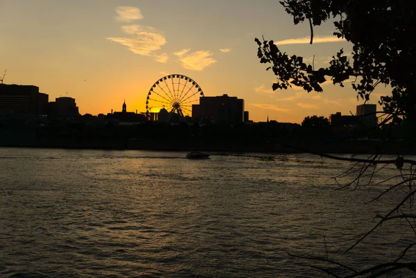 Montreal Grand Ferris Wheel in Old Port at sunset. Reflections of sun rays on Saint Laurent river with a background of cloudy blue sky