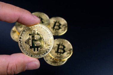 Siyah arka planda bitcoin tutan insan parmakları