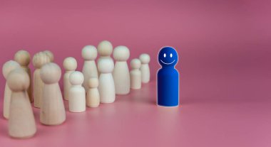 Liderlik ve takım lideri için iş dünyası ve insan kaynakları kavramı. Tahta bebeklerden biri öne çıkıyor. Farklı ve gruptan uzak duruyor.