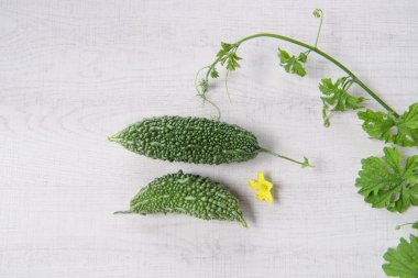 Bitter gourd or bitter melon with vine on wooden background.