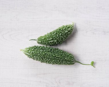 Bitter gourd or bitter melon isolated on white wooden background.
