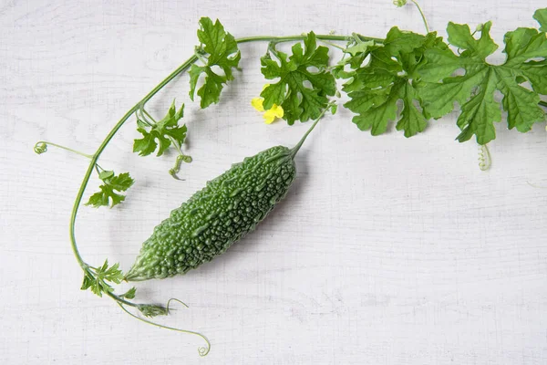 Bitter gourd or bitter melon with vine on wooden background.
