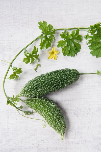 Bitter gourd or bitter melon with vine on wooden background.