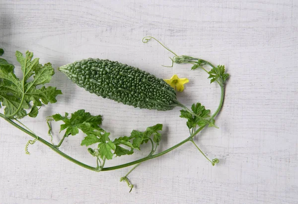 Bitter gourd or bitter melon with vine on wooden background.