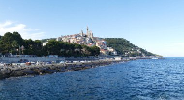 Cervo, İtalya - 04-07-2021: Özgün kayaları ve arka planda güzel bir kasabası olan Cervo plajı