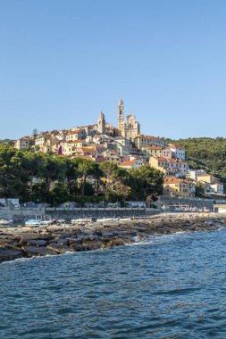 Cervo, İtalya - 04-07-2021: Özgün kayaları ve arka planda güzel bir kasabası olan Cervo plajı