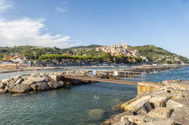 Cervo, İtalya - 04-07-2021: Özgün kayaları ve arka planda güzel bir kasabası olan Cervo plajı