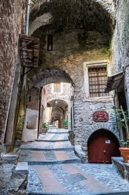 Dolceacqua, İtalya - 06-07-2021: Dolceacqua 'nın tarihi merkezinde kemer ve çiçeklerle birlikte karakteristik küçük sokaklar