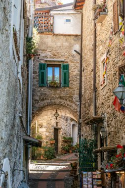 Dolceacqua, İtalya - 06-07-2021: Dolceacqua 'nın tarihi merkezinde kemer ve çiçeklerle birlikte karakteristik küçük sokaklar