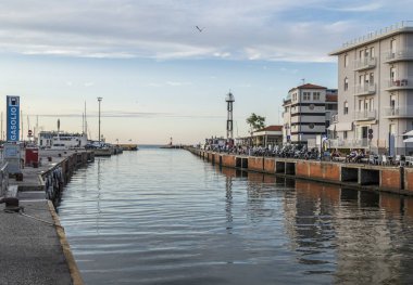 Cattolica, Italy - 04-08-2021: The canal that divides Cattolica from Gabicce with the buildings that are reflected in the water at sunset