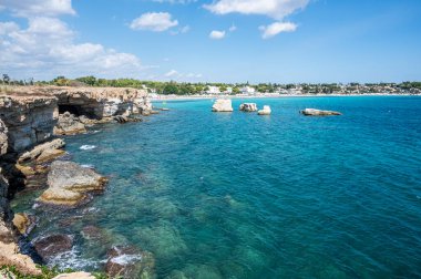 Sicilya, Syracuse 'da arkaplanda Fontane Bianche plajı olan berrak ve kristal turkuaz suyu olan güzel bir uçurum.