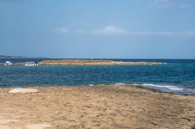 Siraküza 'daki güzel Ognina sahilinde turkuaz, yeşil su ve önünde küçük bir ada var.