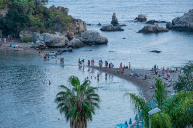 Taormina, İtalya: 09-16-2022: Isola Bella ile Taormina plajı arasında denizi aşan banyolar