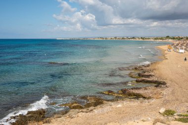 Portopalo di Capopassero 'da kum, turkuaz ve yeşil su ve kum tepeleri olan güzel bir sahil.