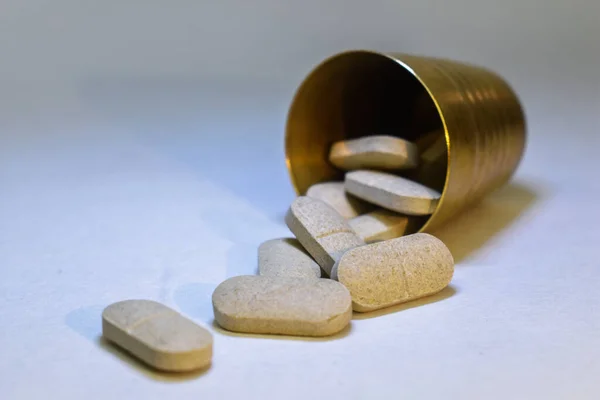 Pills Spilling Out Small Brass Glass White Background — Foto de Stock