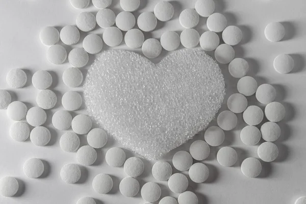 Pills around the heart on a white background. Concept of heart disease.