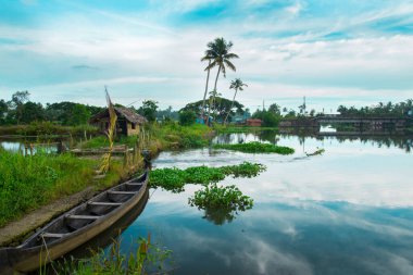 Tahta Tekne Sahilde, tipik palmiye ağaçları ve eski kulübe, Kerala Sahili, Kerala durgun suları gündüz çekimleri Kadamakkudy Kerala, hindistan cevizi ağaçları çizgileri bulutlu bir gökyüzü ve nehir arasında..