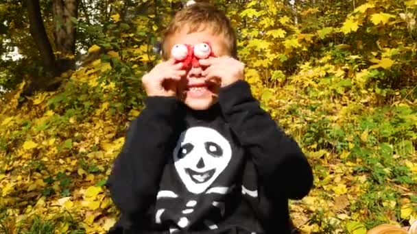Niño Con Traje Esqueleto Negro Apoya Sus Aterradores Ojos Rojos — Vídeo de stock