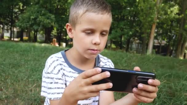 Roztomilý Chlapec Pruhovaném Tričku Nadšeně Hraje Elektronickou Hru Svém Smartphonu — Stock video