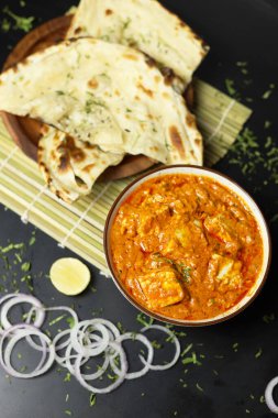 Paneer Butter Masala naan ekmeği, soğan halkaları ve limonla servis edilir, siyah bir zemin üzerinde yazı için yer vardır, Hint köri.