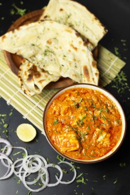 Paneer Butter Masala naan ekmeği, soğan halkaları ve limonla servis edilir, siyah bir zemin üzerinde yazı için yer vardır, Hint köri.