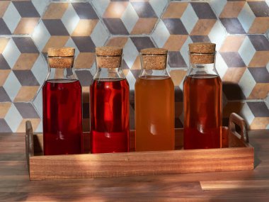 Dört şişe soğuk meyve çayı, robolar, yeşil ve siyah, ahşap bir masada ahşap bir tepside.