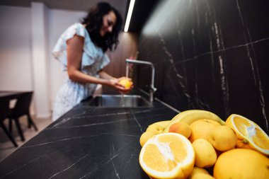 Bir kadın lavaboda meyve yıkıyor.