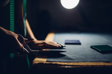 Terzi kumaşı makasla keser. Kişisel standartlara göre giysi üretimi elle yapılır. Moda endüstrisi. Moda tasarımcısı evde çalışıyor.