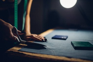 Terzi kumaşı makasla keser. Kişisel standartlara göre giysi üretimi elle yapılır. Moda endüstrisi. Moda tasarımcısı evde çalışıyor.